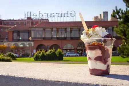 Une coupe glacée au chocolat se trouve au premier plan avec la place Ghirardelli en arrière-plan.